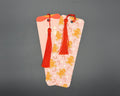Pink gingerbread and candy cane paper bookmark with rounded corners and red fabric tassel. 