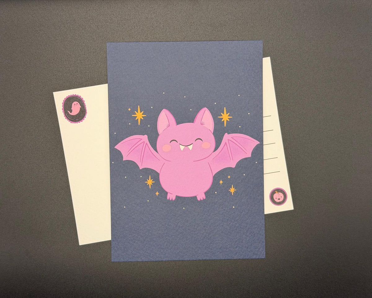 A6 Halloween postcard with cute pink bat against a night sky with ochre stars. 