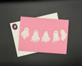 A pink postcard featuring five cute white ghosts hanging on a clothesline.