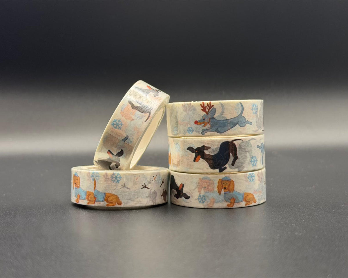 Winter Dachsund whimsical washi tape. Dachsunds running, one wearing a blue jumper, one just running and another with reindeer antlers and a red nose. 